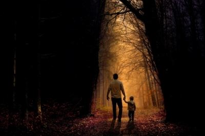 man and child walking through forest